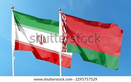 Iran flag and Belarus flag on cloudy sky. waving in the sky Royalty-Free Stock Photo #2295757529