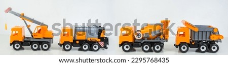 Construction vehicles lined up in a row. Multi-colored children's toys plastic trucks on a white background.