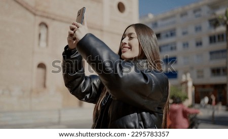 Young beautiful hispanic woman smiling confident making photo by the smartphone at street