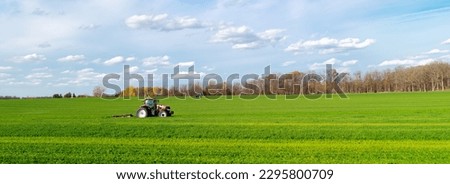 Panorama view large grassy farmland meadow field with working tractors rotary cutter trailer, colorful fall foliage cloud sky in South Lockport, Niagara County, New York, USA. Agriculture industrial