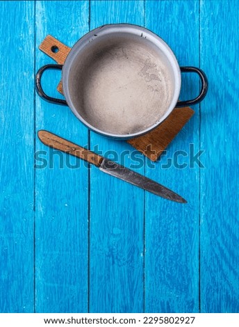 Empty old enamel pot and rustic knife on navy blue boards. Copyspace. Vertical photo.
