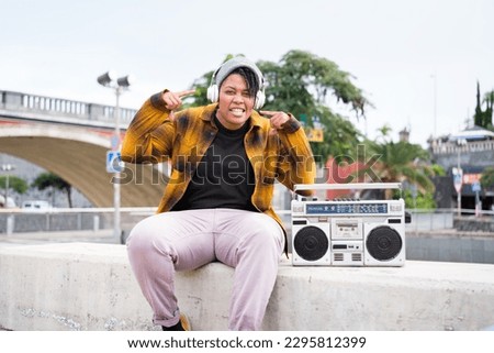Young woman rapping in the street next to her vintage boom box. Concept: freestyle, lifestyle, music