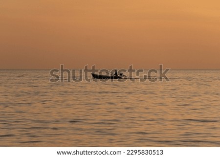 Lonely silhouette of fisherman with his boat at sunset