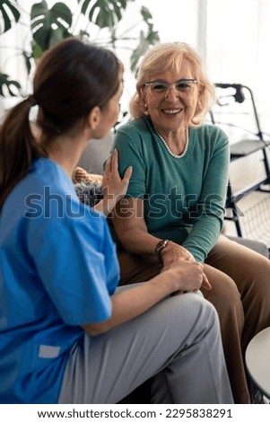 Happy satisfied senior woman holding hands with nurse, enjoying her company and kindness. Lovely elderly woman talking to healthcare specialist during home visit. Home care for people in retirement. Royalty-Free Stock Photo #2295838291