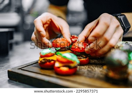 chef hand cooking set mini hamburgers, mini burgers on restaurant kitchen Royalty-Free Stock Photo #2295857371