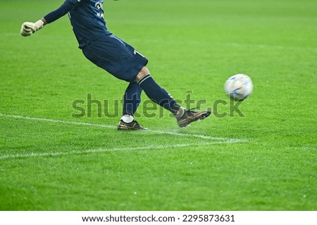 Football goalkeeper kicks ball. Player's legs and the ball during soccer match. Royalty-Free Stock Photo #2295873631