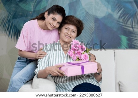 indian young girl with mother giving flowers and present celebrating Happy mothers day
