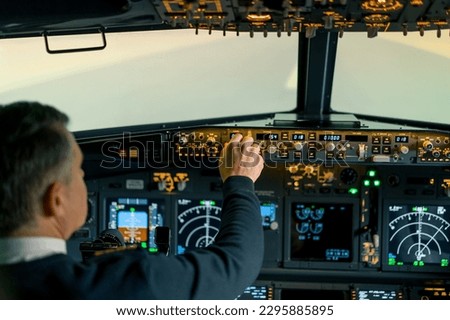 The pilot presses the power buttons on the control panel to control the aircraft in front of cockpit windshield Royalty-Free Stock Photo #2295885895