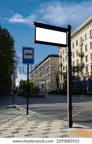 Vertical image of an empty information sign at a bus stop against the backdrop of the city. Template for design.