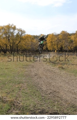 Dirt bike rider flying towards screen in the air with autumn trees in background