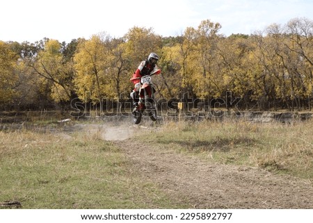 Dirt bike rider flying towards screen in the air with autumn trees in background