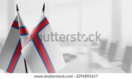 Small flags of the Faroe Islands on an abstract blurry background.