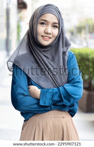 Confident modern young muslim woman crossing arm, outdoor urban background