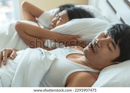 Husband snoring in bedtime. wife suffer unhappy and not sleeping because noise from snoring. Snoring is problem in married relationship Royalty-Free Stock Photo #2295907475
