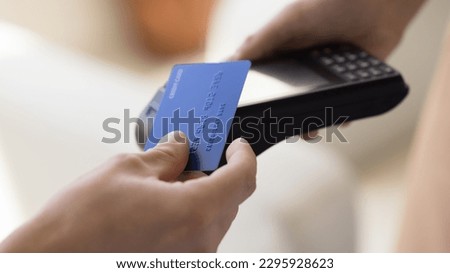 Close up crop view unknown male makes easy, convenient e-payment, holds plastic card against contactless payment terminal equipment, paying for services, food or shopping use wireless NFC technology