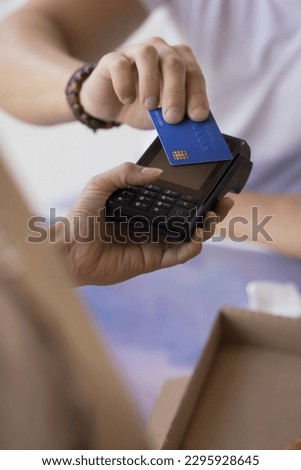 Man purchasing goods, commercial services, paying bills, makes cashless contactless quick payment for order applies credit card on POS terminal cashier machine, close up vertical view. NFC technology Royalty-Free Stock Photo #2295928645