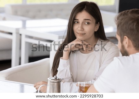 Pretty millennial woman sit at table in cafe on dating with boring man, looks with him with disbelief and disinterest. Bad first impression, problems in relationships, unsuccessful speed blind dating Royalty-Free Stock Photo #2295928703