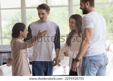 Indian woman greets best friends meet in modern cafe, looks surprised welcoming, hugging guys and girl, stand together, enjoy friendship gather in public place, express warmth and friendly relations Royalty-Free Stock Photo #2295928755