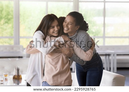 Multi ethnic girls, best friends greet, meet each other in lounge cafe, hugging with love and affection, express warmth, enjoy their strong friendship gathered in public place. Communication, congrats