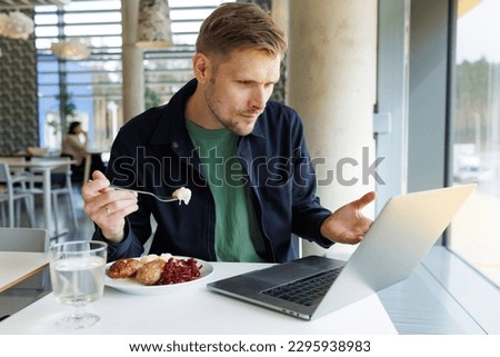 Young male entrepreneur working from a cozy lounge, taking a break to enjoy a healthy eating lunch and watch a video. Reflects a modern workplace that emphasizes mindfulness and healthy living Royalty-Free Stock Photo #2295938983