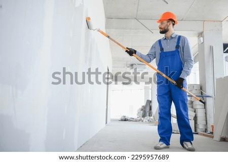 painter man painting the wall, with paint roller. Royalty-Free Stock Photo #2295957689