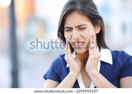 Stressed woman suffering tmj disorder complaining in the street Royalty-Free Stock Photo #2295959107