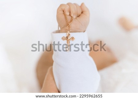 The sacrament of the baptism of a child. The kid is holding a cross. Selective focus. People.