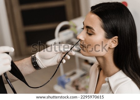 ENT doctor using fibrolaryngoscope to examine and treat nose. ENT specialist diagnoses and treats larynx and pharynx, such as hoarseness, vocal cord nodules, tumors, infections, and inflammation Royalty-Free Stock Photo #2295970615