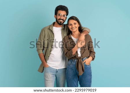 Portrait of cheerful happy stylish beautiful young indian couple hipsters posing together on colorful studio background, embracing and smiling at camera. Love, relationships, affection