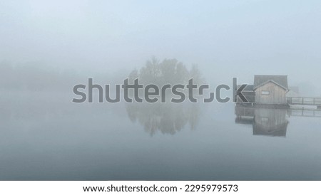a wooden house floating on a lake during a foggy day