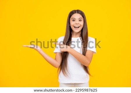 Impressed teenage girl showing recommendation copyspace. Child teenager points away, pointing aside at copy space. Happy teenager portrait. Smiling girl.