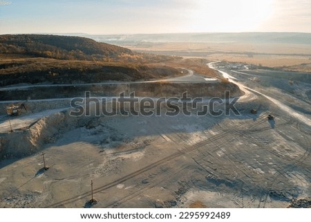 Aerial view of open pit mining site of limestone materials for construction industry with excavators and dump trucks