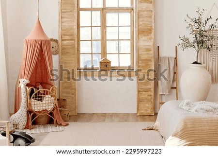 Light playroom interior with rattan crib with canopy, wicker baskets, toys and big window