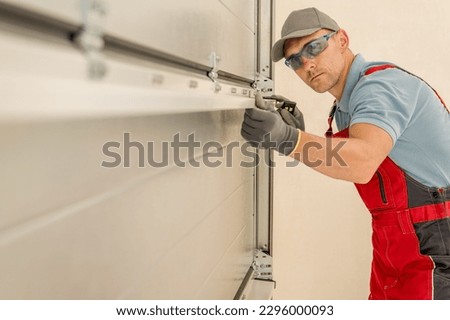 Installing Brand New Residential Garage Doors by Professional Caucasian Technician in His 40s.  Royalty-Free Stock Photo #2296000093