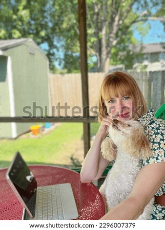 Attractive young woman taking selfies outside on a porch on a beautiful day