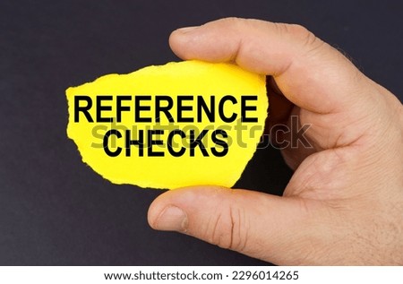 Business concept. On a black background, in the hands of a man, a yellow torn cardboard with the inscription - REFERENCE CHECKS