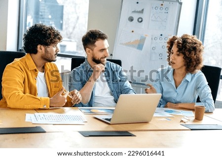 Design team. A group of successful multiracial colleagues, creative designers, brainstorming in the office, developing a concept for a new design project, planning details, discussing ideas, smile Royalty-Free Stock Photo #2296016441