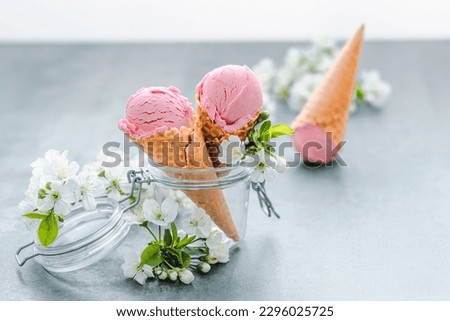 Close up pink creamy ice cream in a glass jar decorated with bloom. Healthy frozen dessert. 