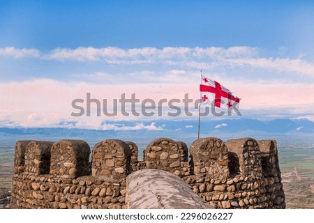 The flag of Georgia waving on bright blue sky background on sighnaghi old walls. 
