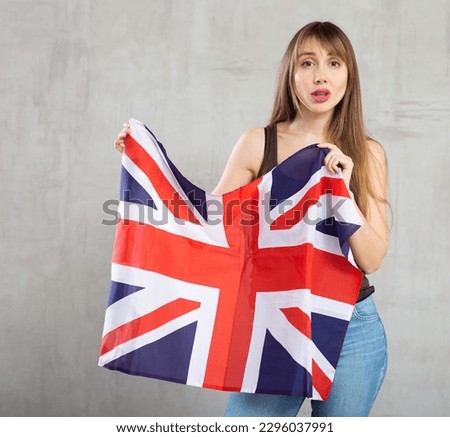 Young sad pretty woman posing tensely with flag of uk