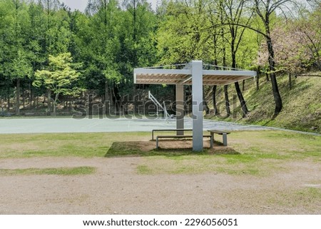 Covered park benches with basketball court in background.