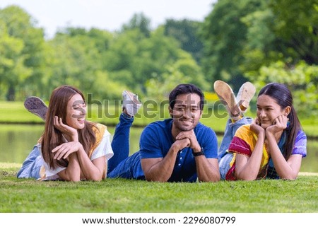 Group of college student friend is relaxingly lying down on the grass in the university campus near the lake for recreation and happiness lifestyle