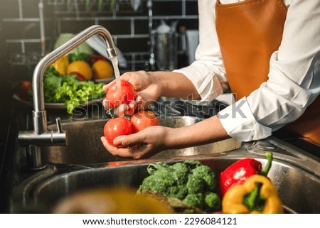 Hand of maid washing tomato fresh vegetables preparation healthy food in kitchen Royalty-Free Stock Photo #2296084121