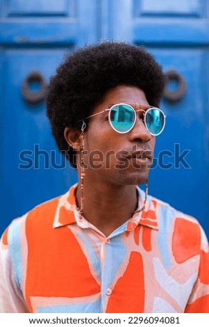 Vertical portrait of young confident and cool black man wearing sunglasses outdoors.