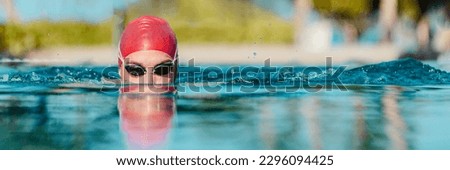 Swimming athlete man creative portrait wearing swim goggles and swim cap in swimming pool while doing breast stroke. Male swimmer swimming breaststroke in pool outside. Panoramic banner.
