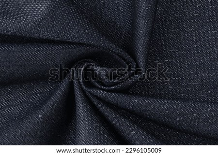 Twisted high quality dark blue tweed fabric with creases used for clothes manufacturing. Saturated textile material texture as background