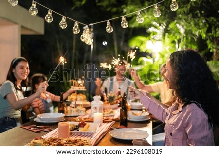 Multi-ethnic big family having fun, enjoy party outdoors in the garden. Attractive diverse group of people having dinner, eating foods, celebrate weekend reunion gathered together at the dining table. Royalty-Free Stock Photo #2296108019