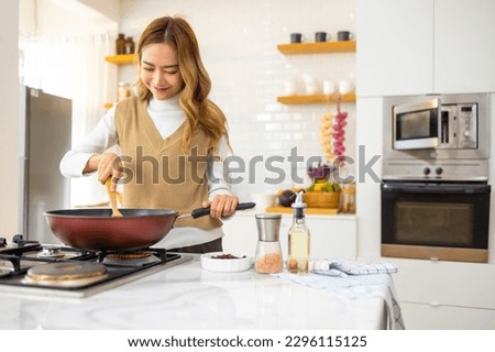 Asian woman hand cooking healthy food pasta and salmon steak on cooking pan in the kitchen at home. Attractive girl preparing food for dinner party celebration meeting with friends on holiday vacation Royalty-Free Stock Photo #2296115125