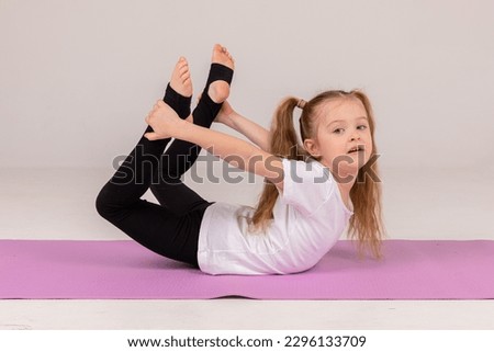 Happy little girl doing gymnastics isolated on white background