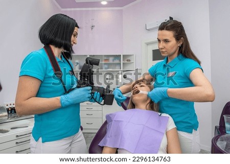 the dentist and his assistant in special clothes take photos of the patient's teeth on the dental chair. Tooth photo concept